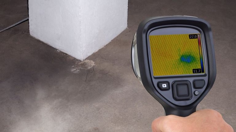 Hidden water leak detection using a thermal imaging camera to identify a cold moisture spot in a concrete floor near a wall.