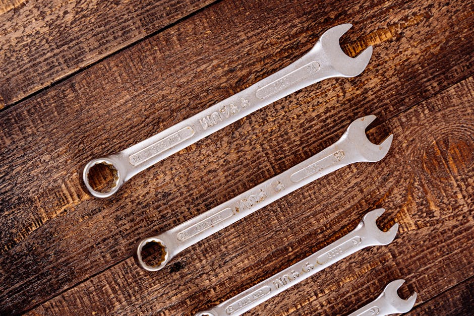 Close-up of metal wrenches on a rustic wooden table in a workshop setting.