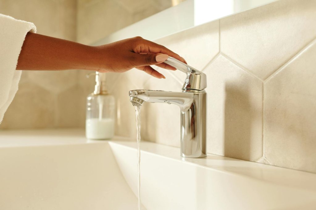 water saving fixtures Gold Coast - hand turning chrome faucet with water flowing