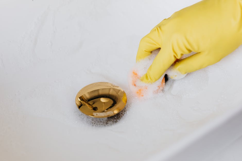 Person in gloves cleaning bathroom sink - how drain cleaner works Gold Coast