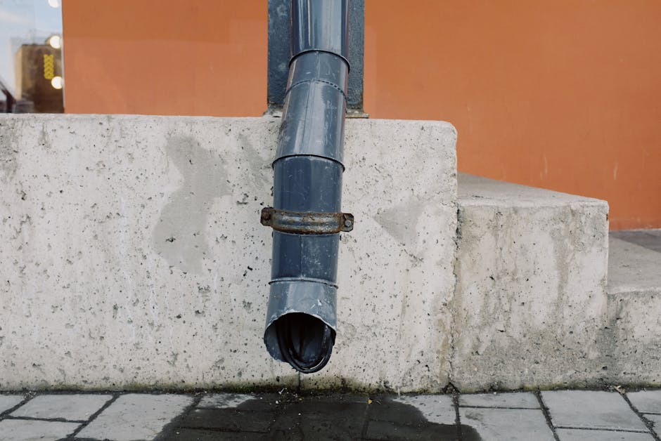 sulfuric acid vs hydrochloric acid for drains - aged metal drain pipe with water stains on concrete wall