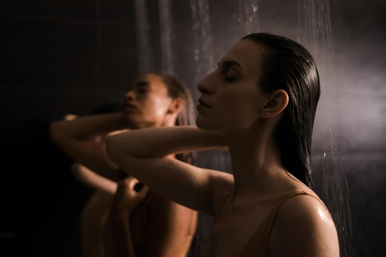 Two women enjoying a calming shower experience in a serene spa environment.